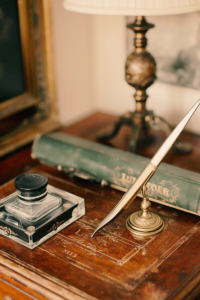 Dip pen and inkwell on antique writing desk.